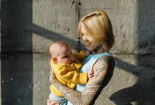 loving mother with newborn baby near concrete wall