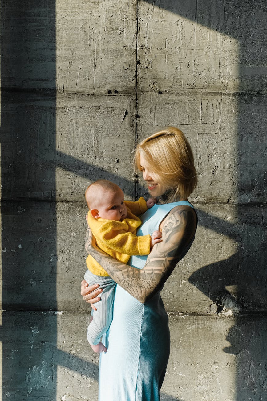 loving mother with newborn baby near concrete wall