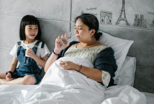 adorable ethnic child giving pills to unhealthy grandmother drinking water in bed