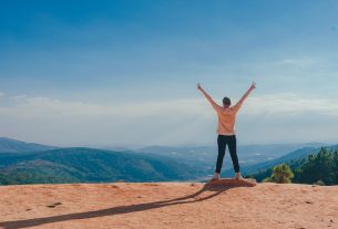 person in beige top on mountain cliff