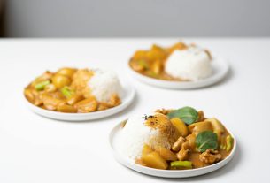 plates with tasty curry placed on white table